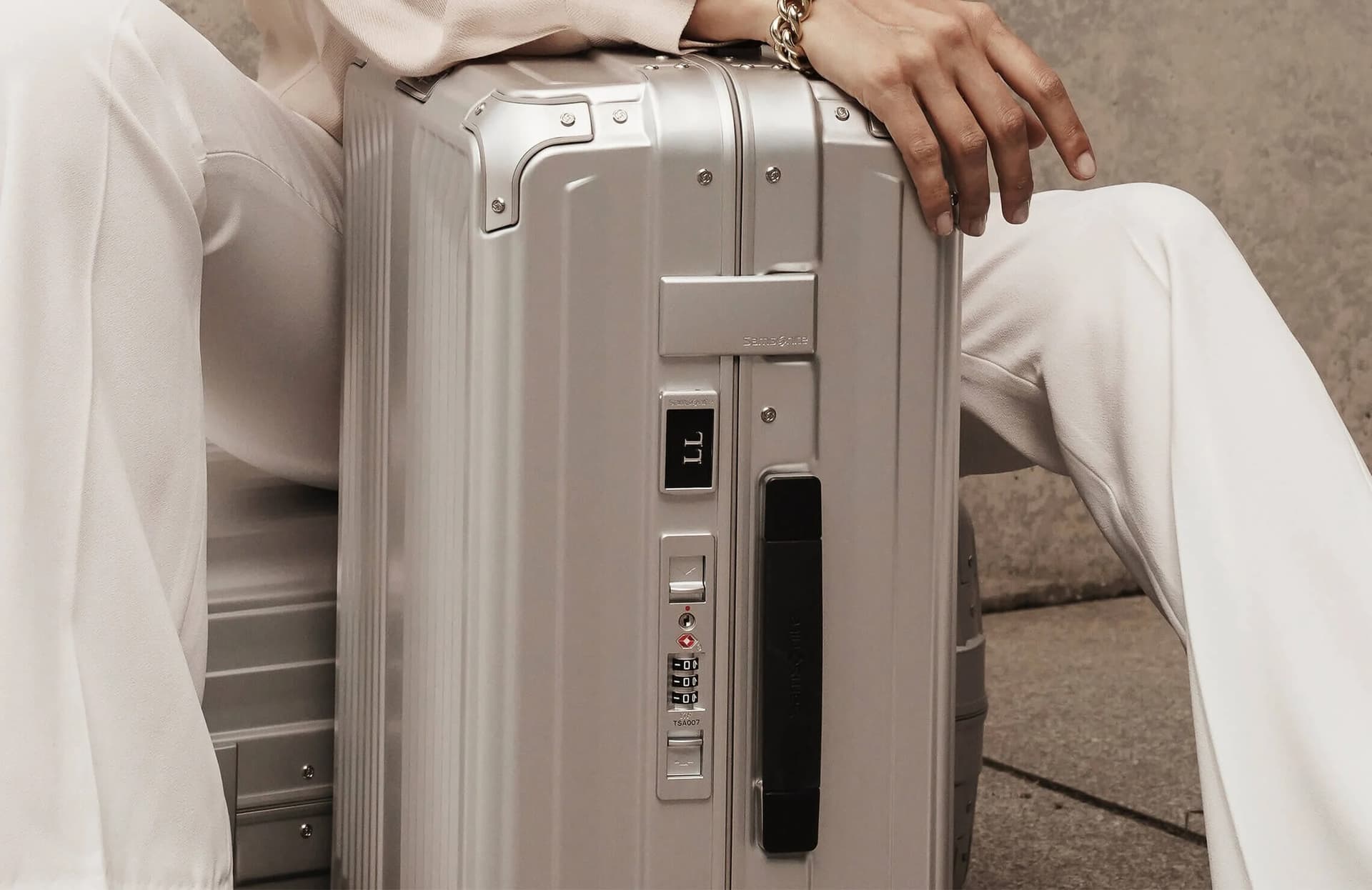 Femme avec valise Tumi aluminium